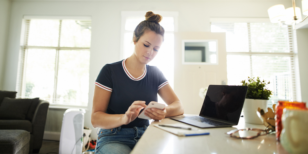 kvinne bruker egen mobil og pc til jobb