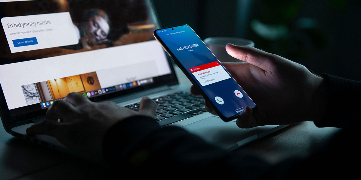 Person sitter med mobil i hånda og svindelvarsel fra Se Hvem
